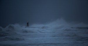 A lighthouse glowing brightly amidst a dark and stormy sea.