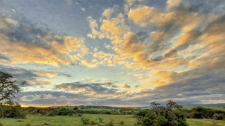 Golden sunrise breaking through dramatic clouds over a quiet African landscape, symbolizing hope after darkness.