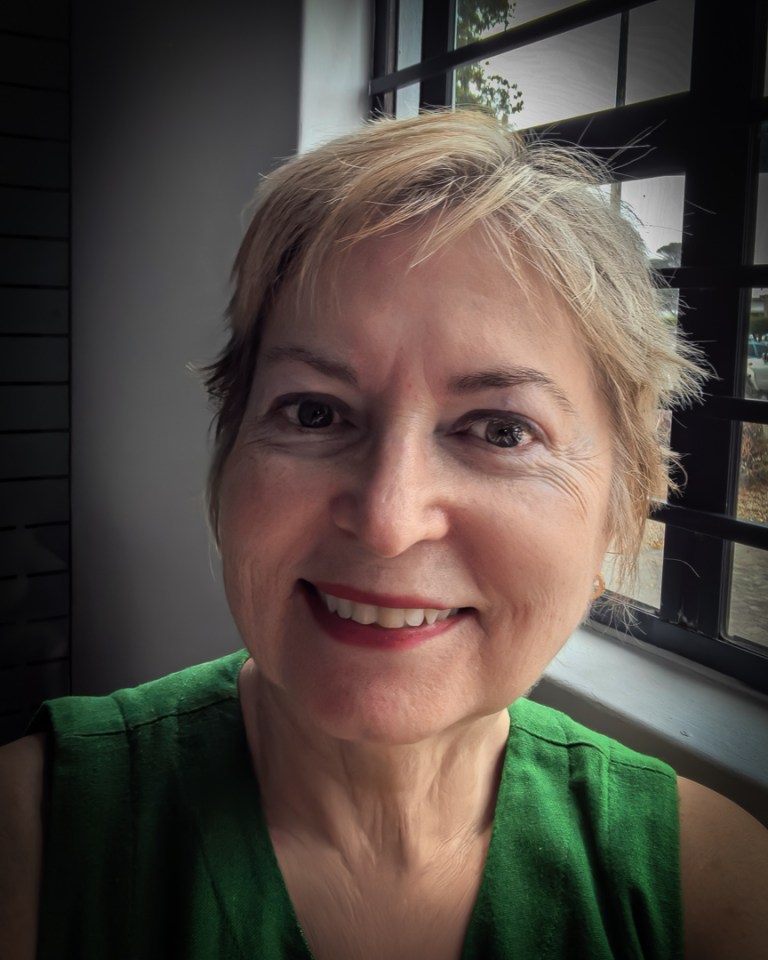 Portrait of a woman on her 70th birthday, smiling softly in natural window light, reflecting gratitude and becoming.