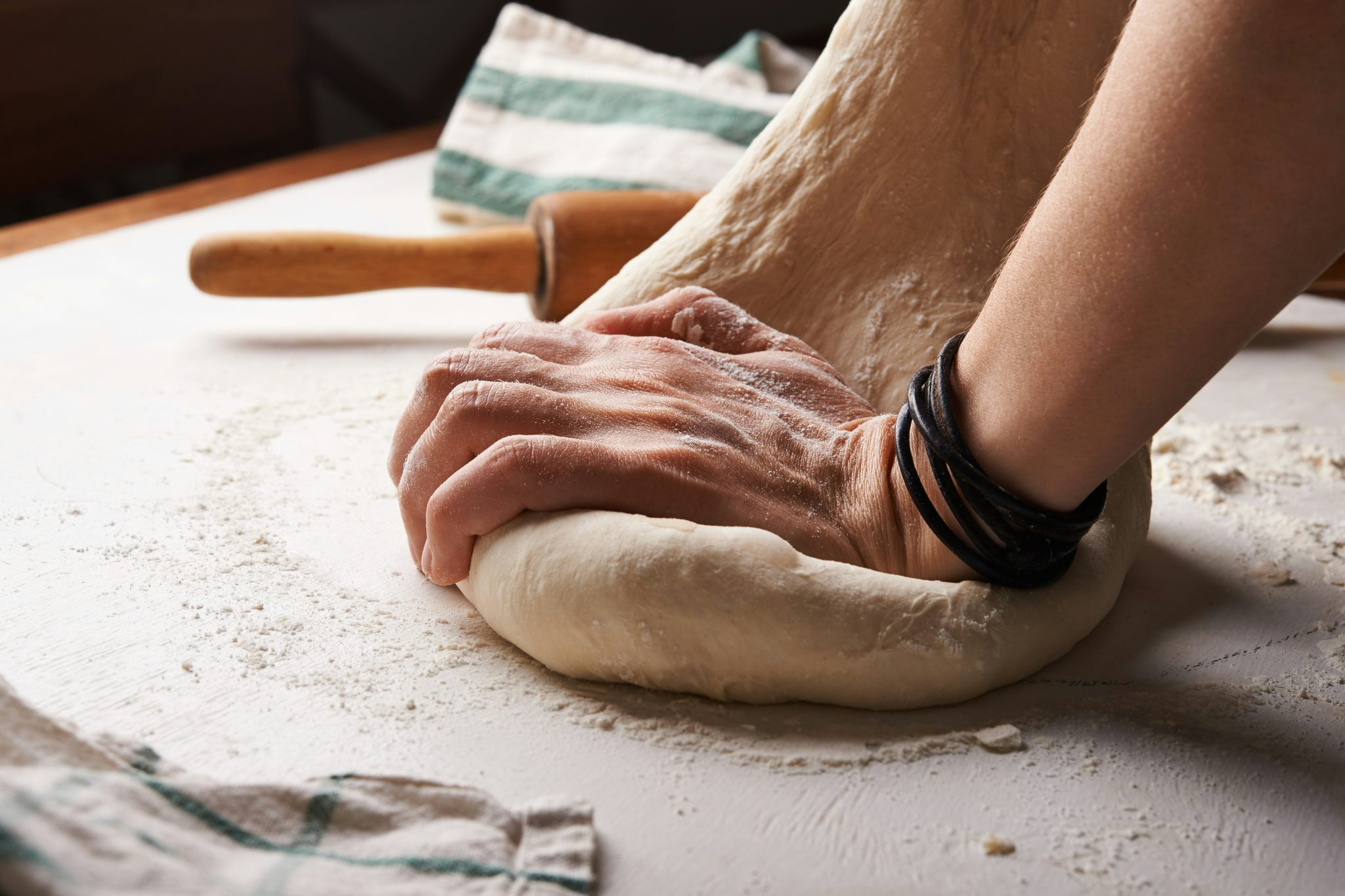 Hands kneading bread dough on a flour-covered table, symbolising a mother’s love expressed through nourishment, patience and sacrifice.